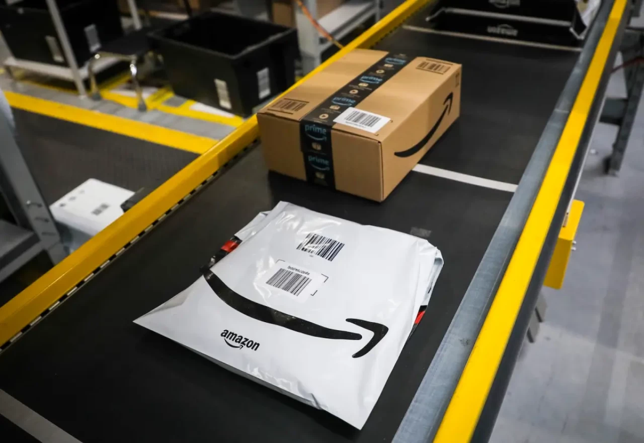 A white shipping packaging and a brown box with the Amazon logo on the conveyor belt. 